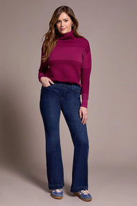 Woman modeling flattering high-rise bootcut jeans with magenta turtleneck