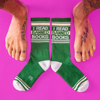 Green socks with 'I Read Banned Books' text surrounded by tattooed bare feet on pink background