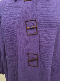 Close-up of indigo jacket with textured fabric and square brown button accents