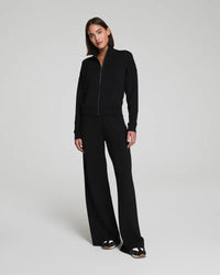 Woman modeling jet black wide-leg lounge pants with matching zip-up jacket