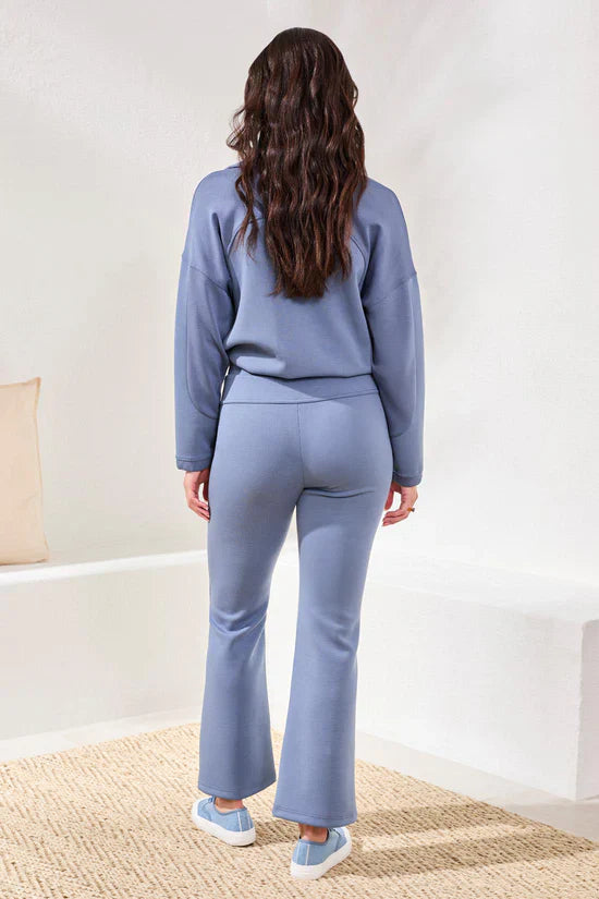 Back view of a woman wearing a lavender lounge set with flared pants and matching sneakers