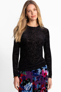 Front view of a woman in a luxe black velvet paisley top styled with floral wide-leg pants