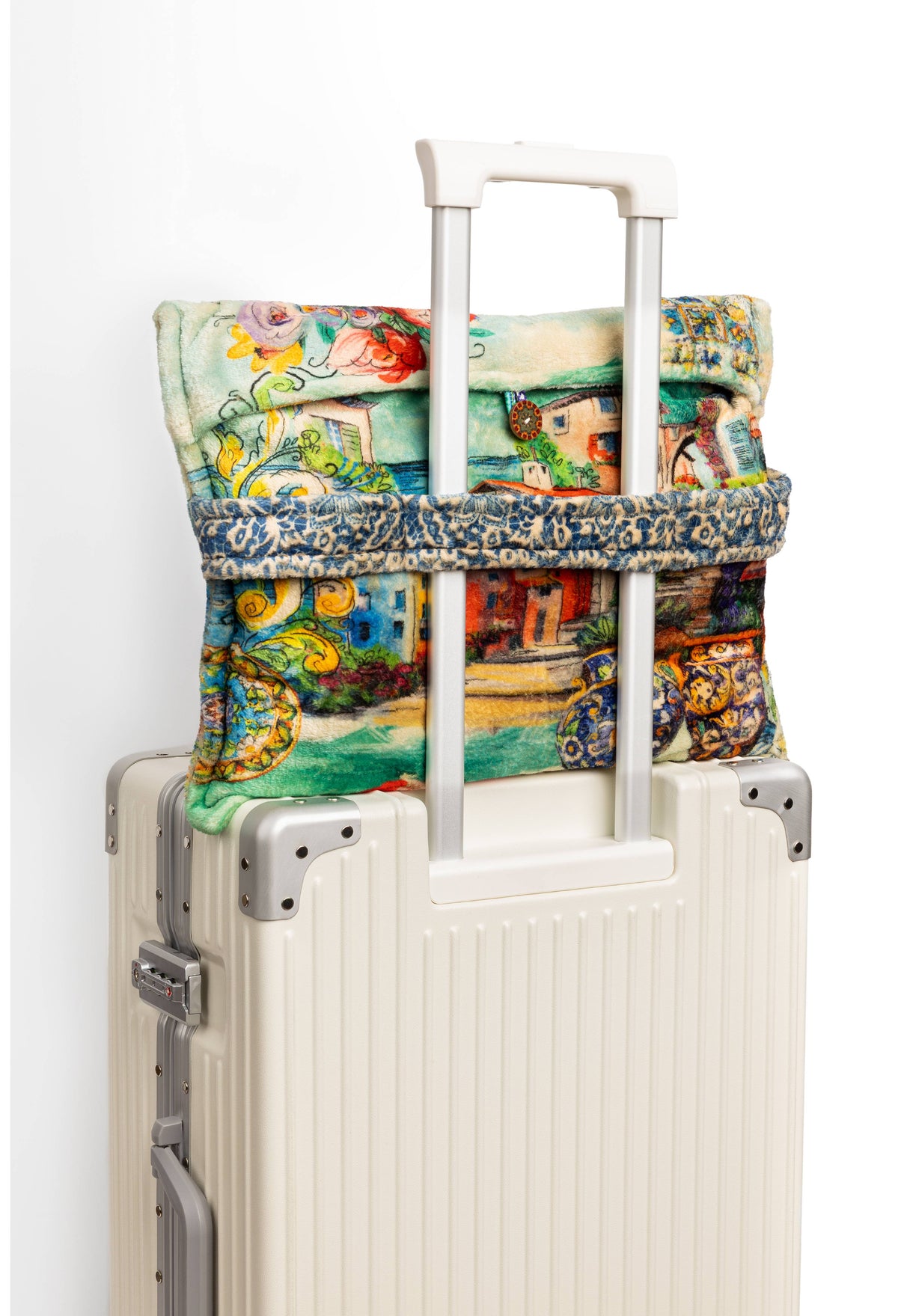 Travel blanket featuring Mediterranean town print sitting on luggage
