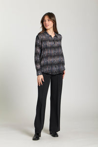 Woman modeling a relaxed fit blouse featuring a black and metallic diamond print with black dress pants