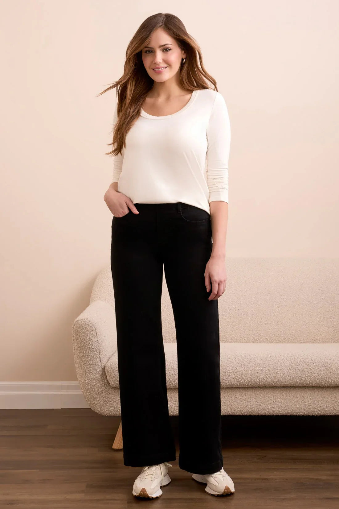 Black wide-leg pants styled with a white top, modeled by a smiling woman
