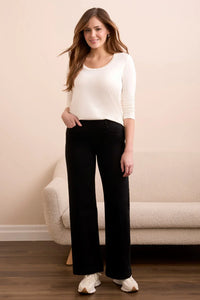 Black wide-leg pants styled with a white top, modeled by a smiling woman
