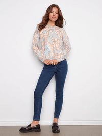 Woman in pastel floral sweater paired with skinny blue jeans and black loafers