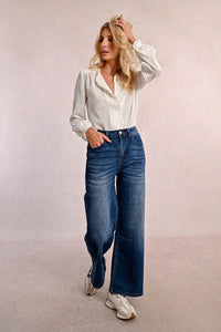 Woman in Molly Bracken wide leg jeans with hands in pocket and stylish white blouse