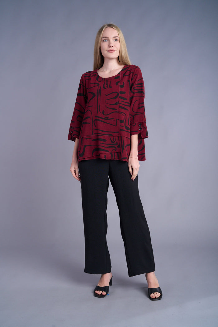 Woman modeling black wide-leg pants with a patterned maroon top