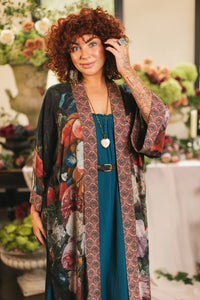 Woman wearing a black kimono robe with colorful floral print and intricate border