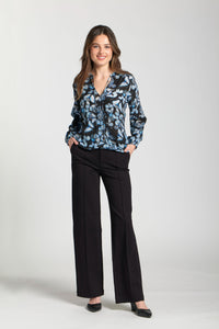 Woman wearing a black blouse with blue butterfly print paired with black pants