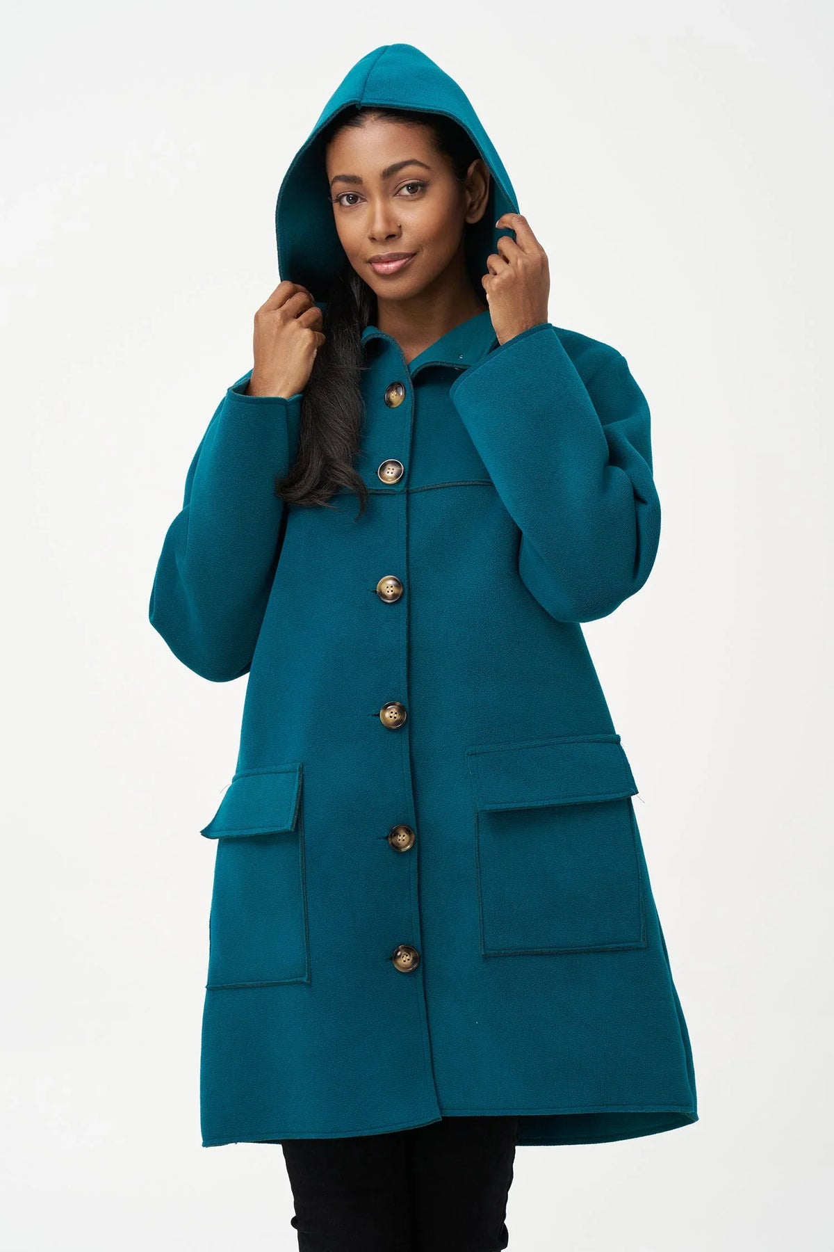 Model in teal hooded wool coat holding hood up