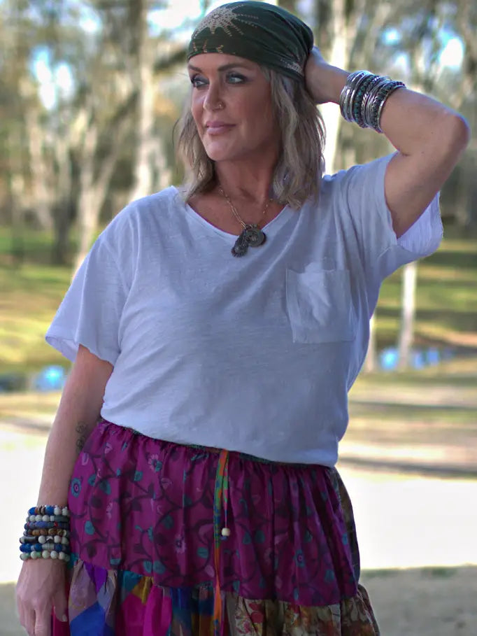 Woman wearing a white V-neck t-shirt styled with a colorful skirt outdoors