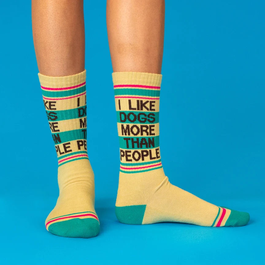 Person wearing cream socks with teal accents and 'I Like Dogs More Than People' visible