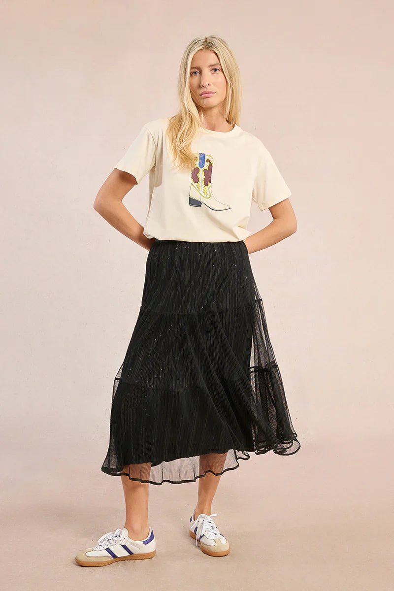 Model in black mesh midi skirt and graphic tee with hands on hips
