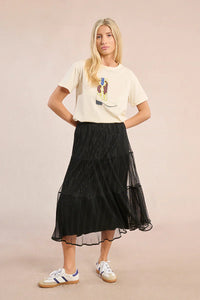 Model in black mesh midi skirt and graphic tee with hands on hips
