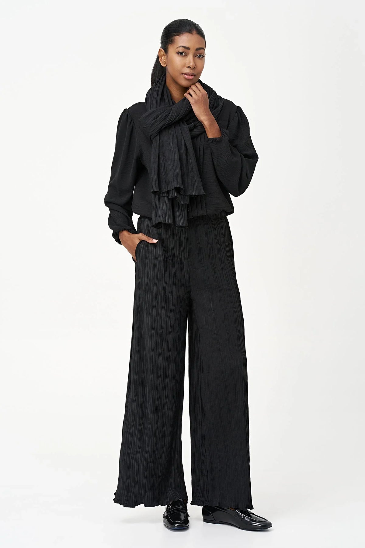 Woman modeling black wave-texture wide-leg pants with matching scarf and blouse