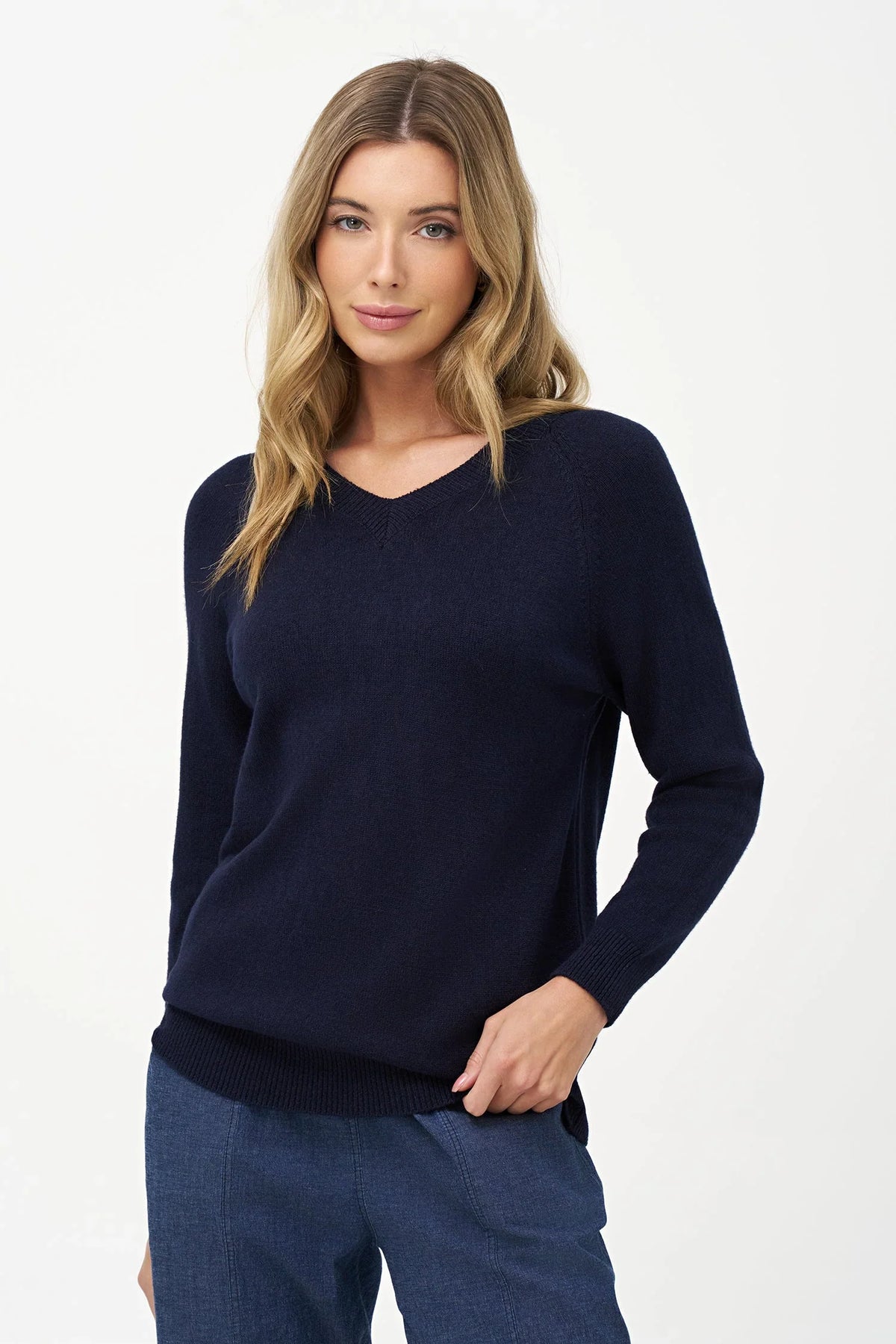 Woman modeling navy V-neck sweater with hand on hip and casual jeans