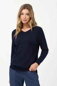Woman modeling navy V-neck sweater with hand on hip and casual jeans