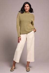 Stylish woman in an olive ribbed mock neck sweater with cream wide-leg pants and gold flats