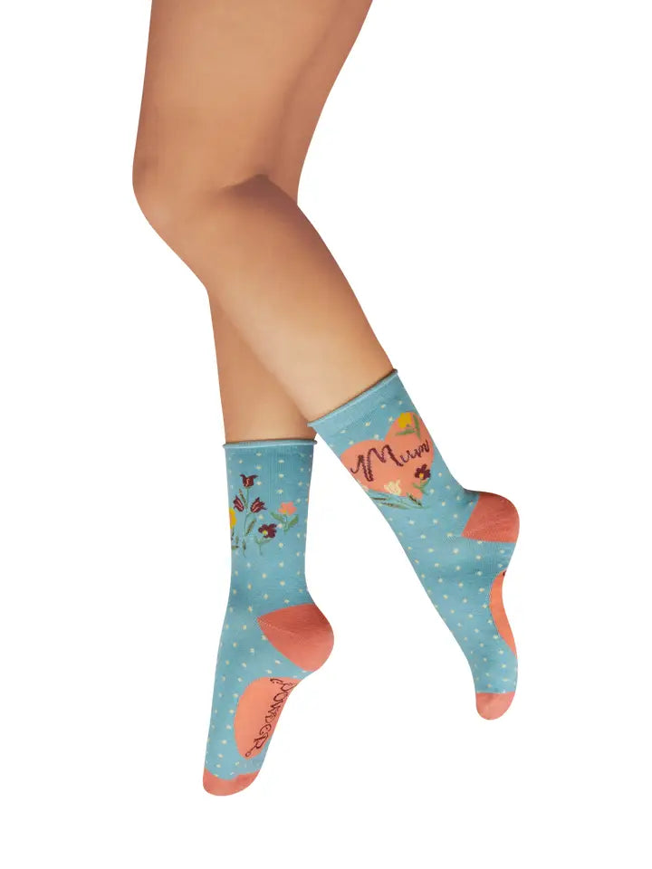 Woman wearing blue socks with polka dots, floral patterns, and 'Mum Power' text