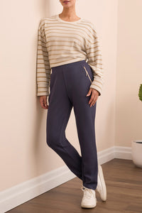 Front view of navy jogger pants with gold zipper pockets styled with striped sweater