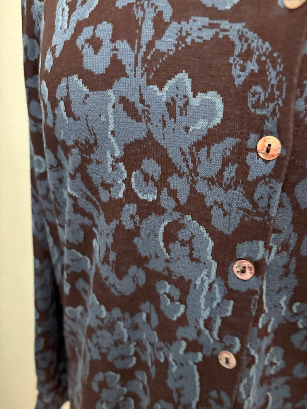 Close-up of navy blue floral jacquard knit pattern with brown background and button details