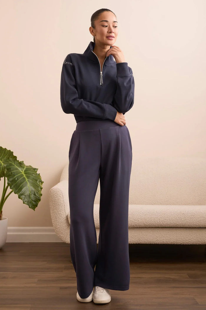 Model in navy lounge set posing thoughtfully with one hand on her chin
