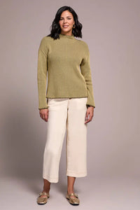 Front-on look of an olive ribbed mock neck sweater paired with cream cropped pants