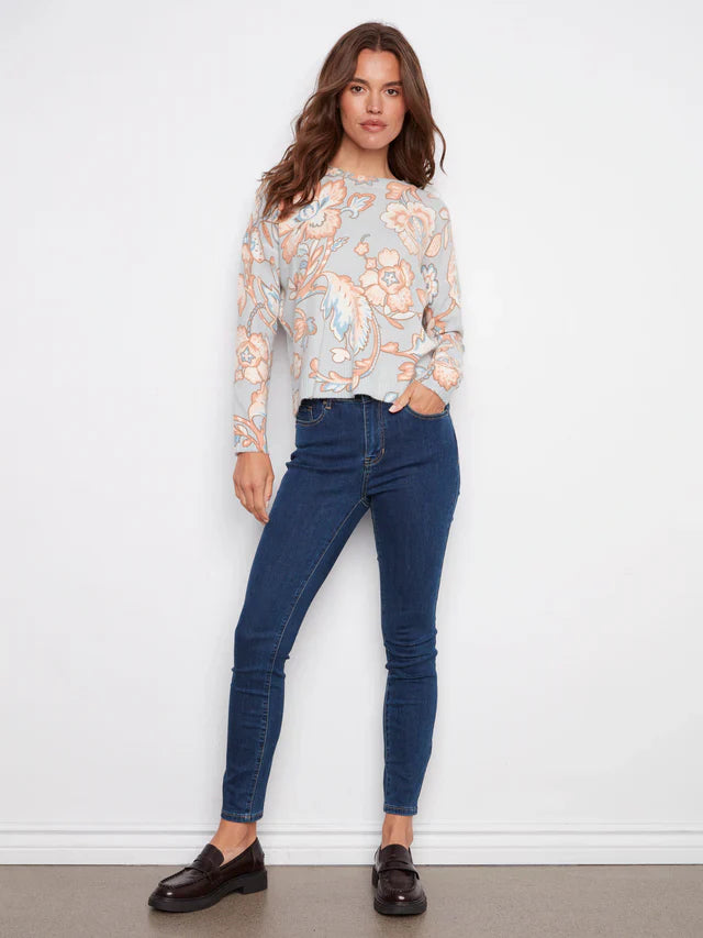 Full body view of woman in pastel floral sweater and dark skinny jeans