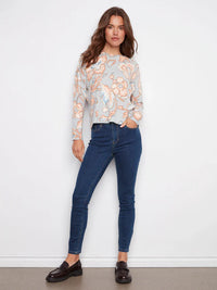 Full body view of woman in pastel floral sweater and dark skinny jeans