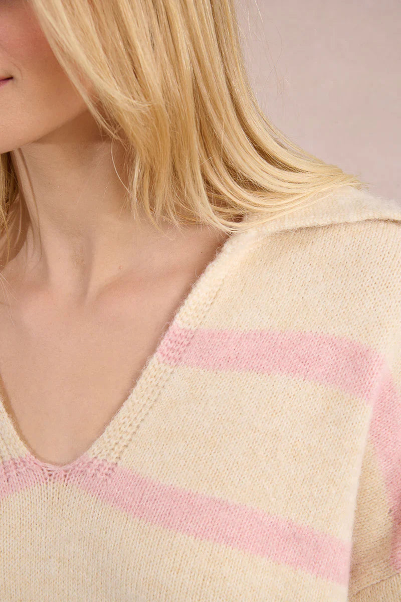 Close-up of a pastel cream sweater with light pink stripes and a V-neck collar