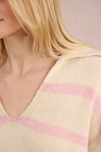 Close-up of a pastel cream sweater with light pink stripes and a V-neck collar