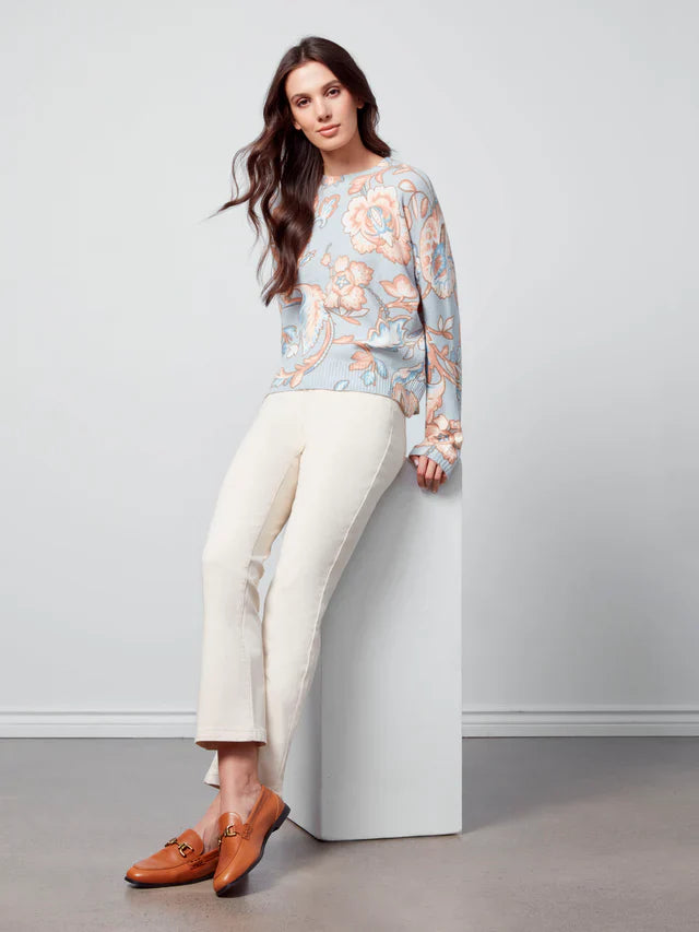 Model wearing pastel floral knit sweater with cream pants and brown loafers