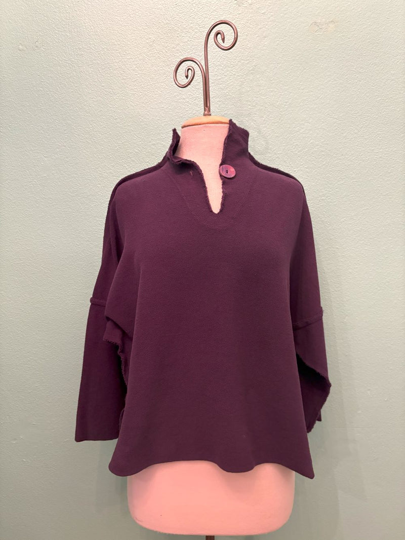 Front view of plum relaxed button neck pullover with raw edge details