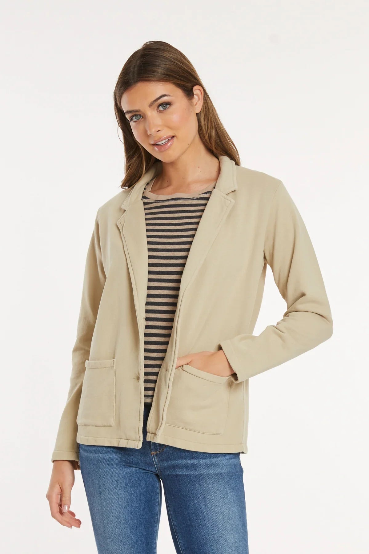 Woman shown from back wearing beige knit blazer with casual blue jeans