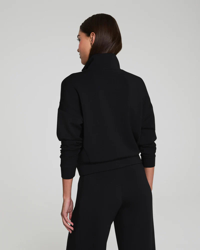 Back view of a woman in a black high-collar track jacket