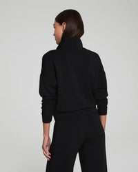 Back view of a woman in a black high-collar track jacket