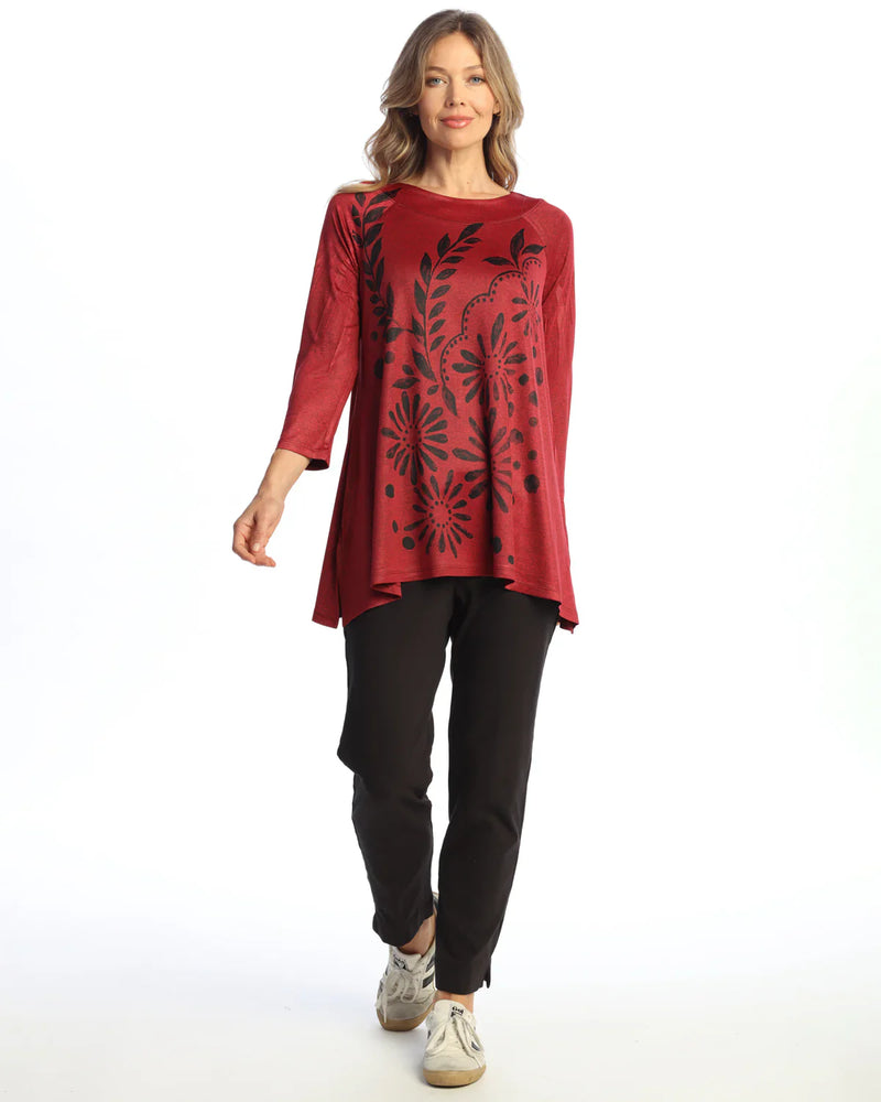 Woman wearing red swing tunic top with black floral print and black pants