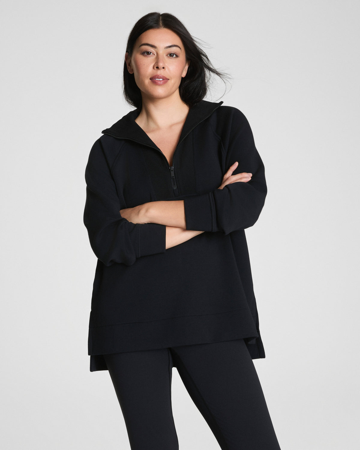 Woman in black quarter-zip pullover, arms crossed, showing relaxed fit