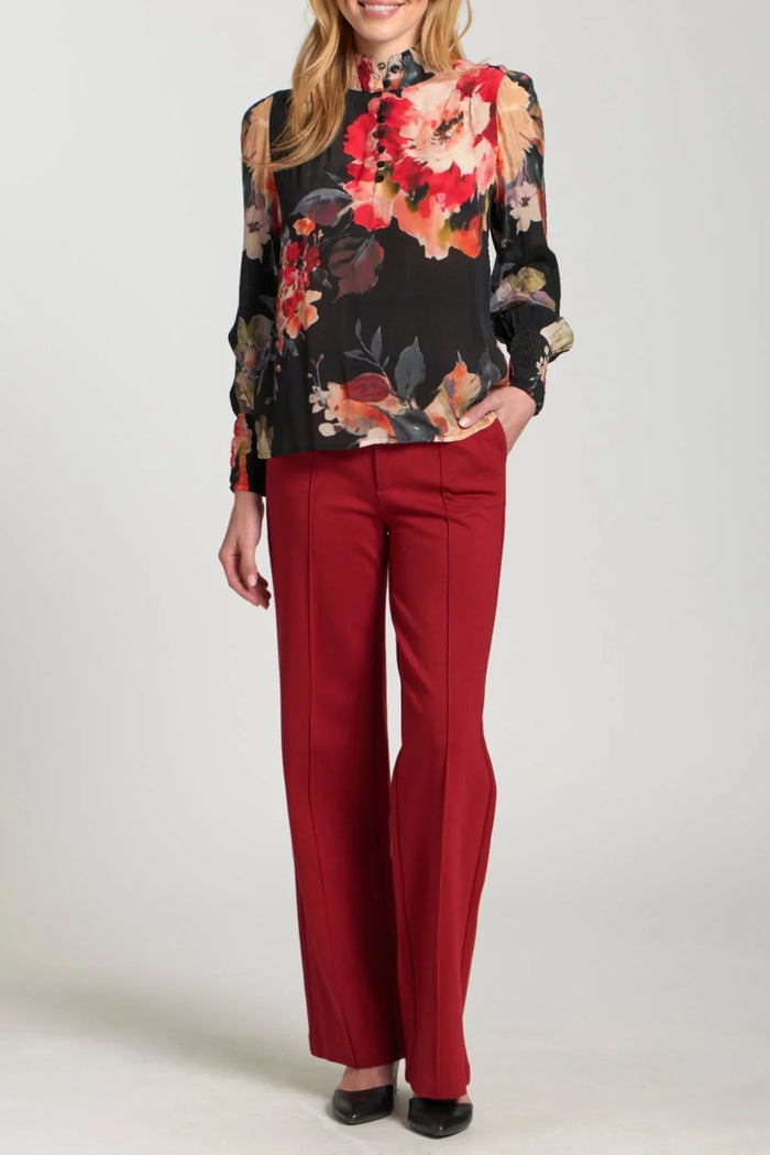 Woman wearing ruby red wide leg trousers paired with a floral blouse