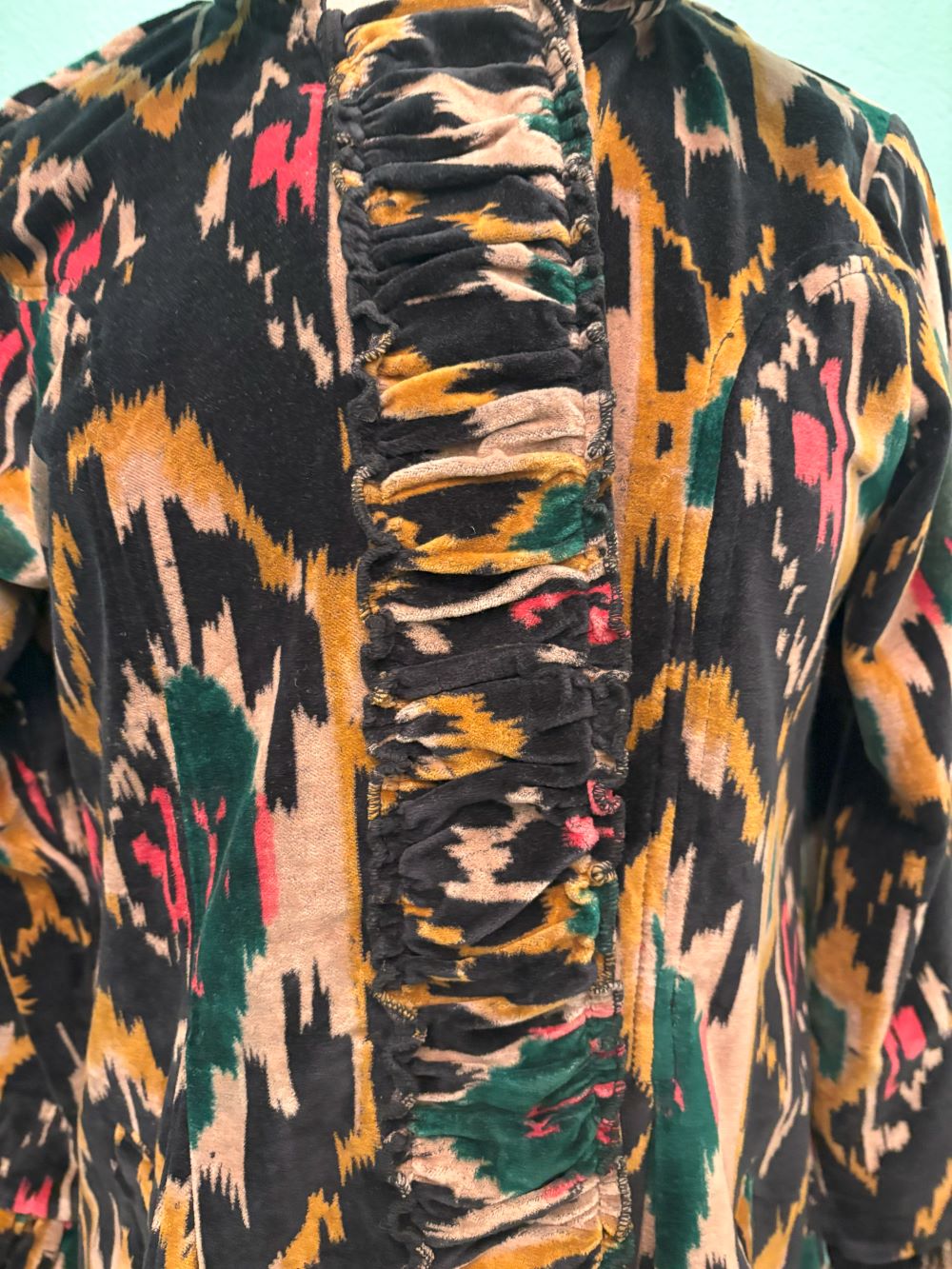 Closeup of the ruched velvet trim and detailed Ikat print on the coat front