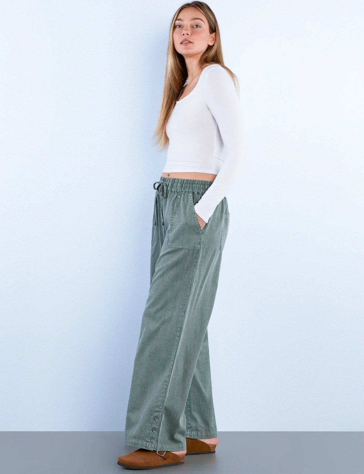 Side view of sage green corduroy wide-leg pants with button details on the hem