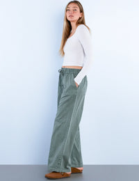 Side view of sage green corduroy wide-leg pants with button details on the hem