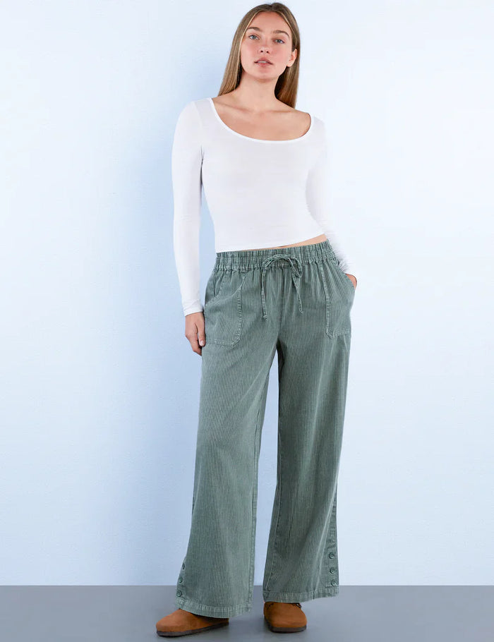 Front view of woman wearing sage green corduroy wide-leg pants with drawstring waist