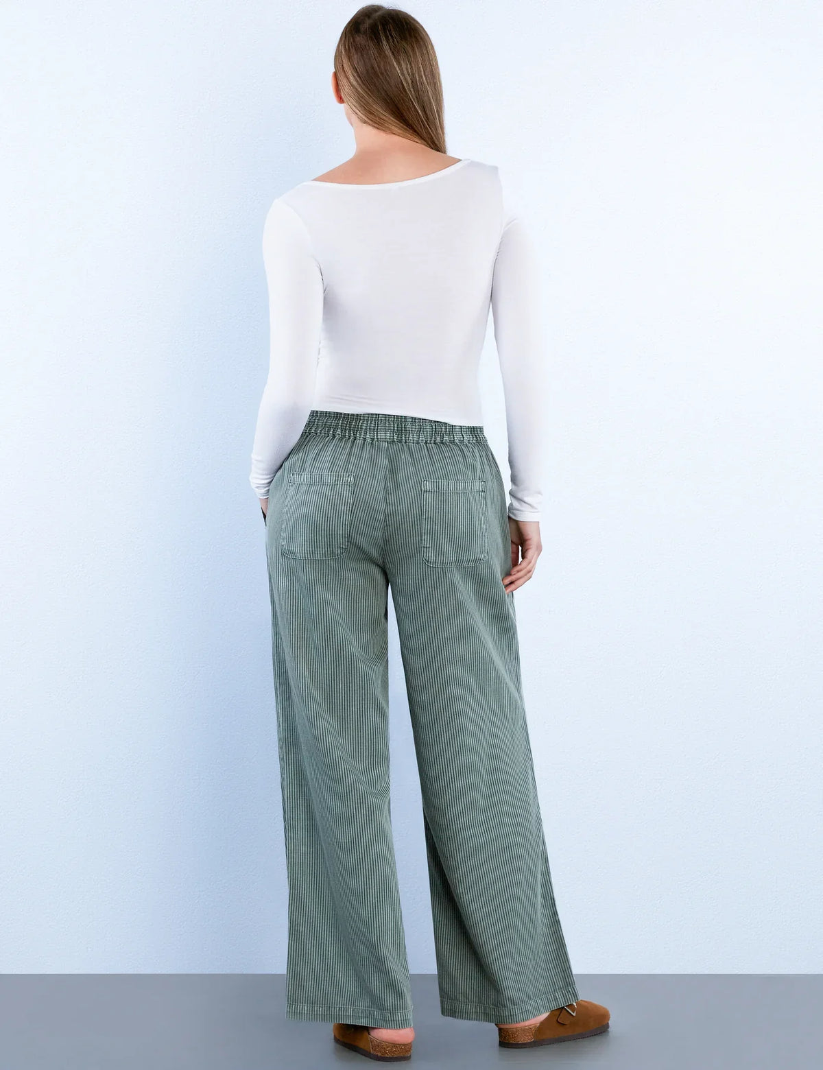 Back view of sage green corduroy wide-leg pants showcasing elastic waistband and pockets