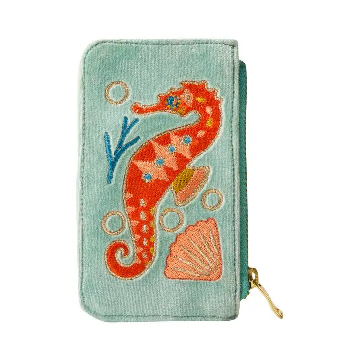 Close-up of mint green velvet wallet featuring detailed orange seahorse and shell embroidery