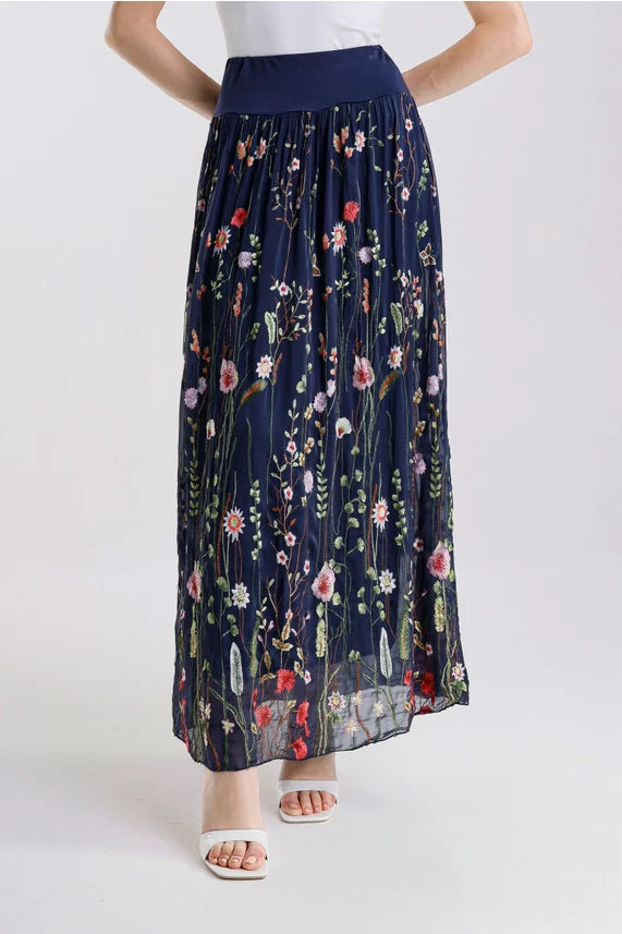 Front view of black floral embroidered maxi skirt, styled with white sandals