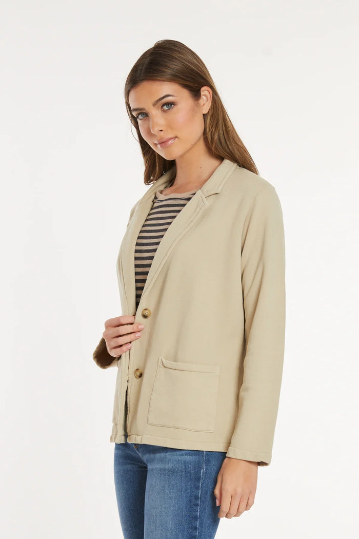 Woman modeling beige knit blazer from a side angle, hand on lapel