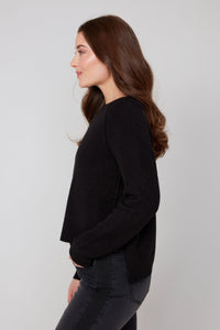Side profile of a woman in a black crewneck sweater paired with dark denim